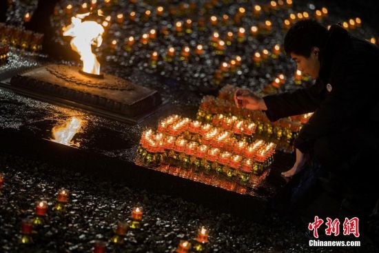12月13日晚，侵华日军南京大屠杀遇难同胞纪念馆内，来自美国、加拿大、韩国、日本等国的友好人士和南京青少年学生，中日两国僧侣以及南京大屠杀幸存者、抗战老兵等共同捧起点燃的蜡烛，为侵华日军南京大屠杀死难者守灵。当日是中国第三个南京大屠杀死难者国家公祭日，南京举行各种形式的活动悼念遇难同胞。泱波 摄