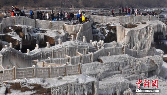 2017年1月1日，随着气温持续下降，山西吉县黄河壶口瀑布溅水成冰，层层叠叠的冰挂悬挂在瀑布两岸的岩石和护栏上，吸引了众多游客和摄影爱好者。中新社发 汪小英 摄 图片来源：CNSPHOTO